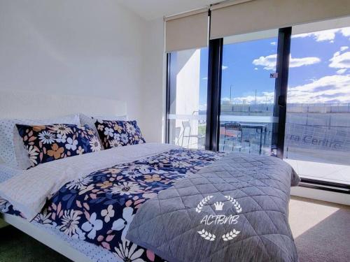 1 dormitorio con cama y ventana grande en City View Lovely 1BD Apartment @ CBD, en Canberra