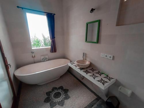 een badkamer met een bad, een toilet en een wastafel bij Kalimaja Amed Villa in Ambat
