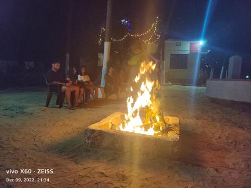 a fire pit with people sitting around it at night at His Grace Camping at Malpe Beach in Udupi
