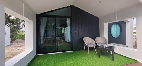 two chairs and a table in a room with green carpet at The Nidhra Boutique Resort in Baan Tai