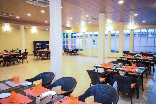 a dining room with tables and chairs with orange napkins at Bougainvillea Retreat & Spa in Kāhārpāra