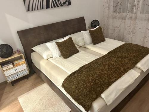 uma cama grande com lençóis e almofadas castanhos e brancos em Unterschlupf em Ebensee