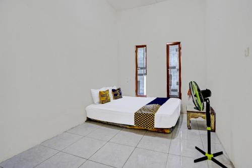 een slaapkamer met een bed en een statief bij OYO LIFE 92077 Tarlo Guest House 3 in Pradahkalikendal