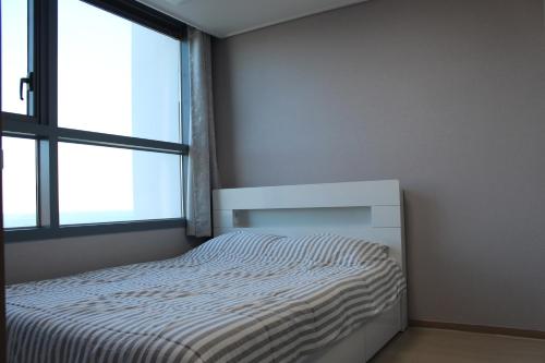 a small bedroom with a bed and a window at Fine and You Ocean City in Donghae