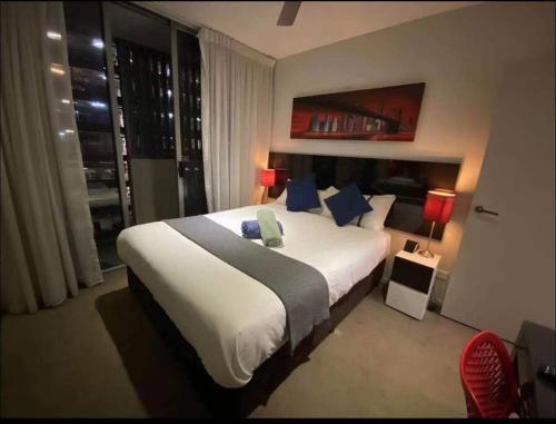ein Schlafzimmer mit einem großen weißen Bett mit blauen Kissen in der Unterkunft CBD 1BED/POOL/GYM/SAUNA/ - CLOSE TO EVERYTHING! in Brisbane