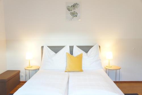 sypialnia z białym łóżkiem z żółtymi poduszkami w obiekcie Schwarzacherhof Pension & Apartments w mieście Schwarzach im Pongau