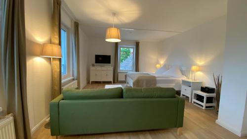 a living room with a green couch and a bed at Villa Rosalie Sassnitz in Sassnitz