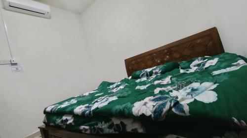 a bed with a green blanket with white flowers on it at Zulaikha's Homestay Ulu Tiram Johor Bahru in Ulu Tiram