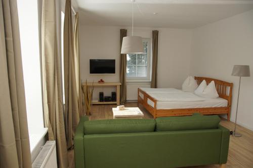 a living room with a green couch and a bed at Villa Rosalie Sassnitz in Sassnitz