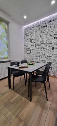 a dining room table and chairs in front of a wall at IO E TE bed and breakfast Appartamento in Cuneo
