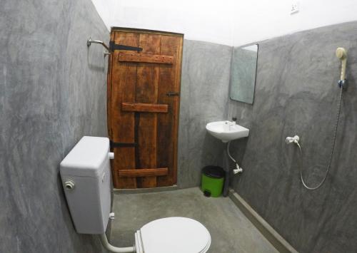Łazienka z drewnianymi drzwiami, toaletą i umywalką w obiekcie 20 House Villa w mieście Arugam Bay