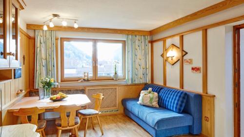 ein Wohnzimmer mit einem blauen Sofa und einem Tisch in der Unterkunft DAS EDELWEISS - Apartment Kuprian in Ried im Oberinntal