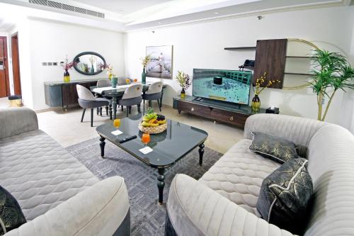 a living room with a couch and a table and a television at Seafront Luxury Suites Jeddah Corniche in Jeddah