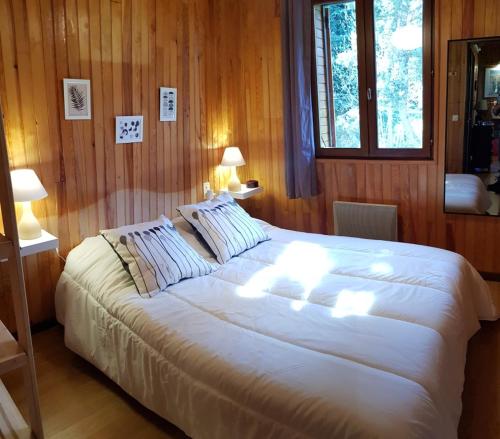 uma grande cama branca num quarto de madeira com 2 candeeiros em Chalet La Campagnette em Eyne