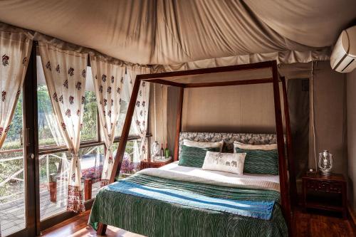 a bedroom with a canopy bed and a window at Bagh Tola, Bandhavgarh Tiger Reserve in Tāla