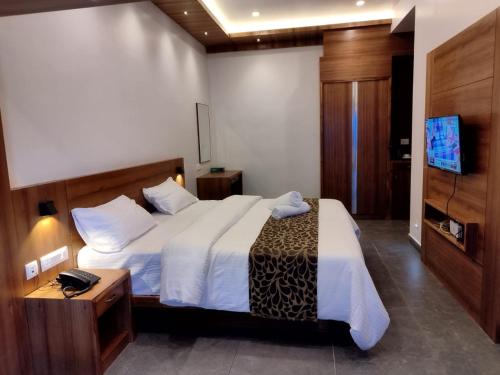 a bedroom with a large bed and a television at The Wild Trails Clarks Exotica , Munnar in Munnar