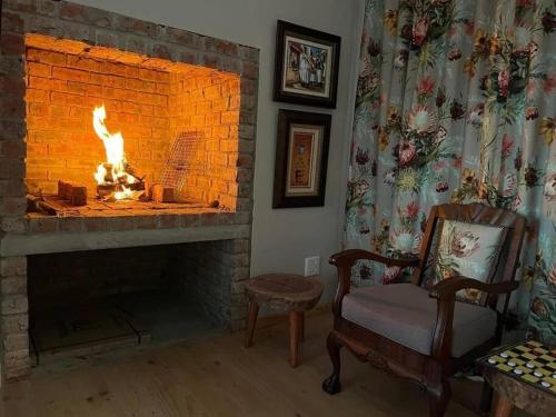a living room with a fireplace with a fire in it at Vredenbosch Hoekwil in Wilderness