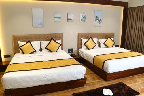 two beds in a hotel room with yellow and white pillows at Rudra Royals in Shirdi