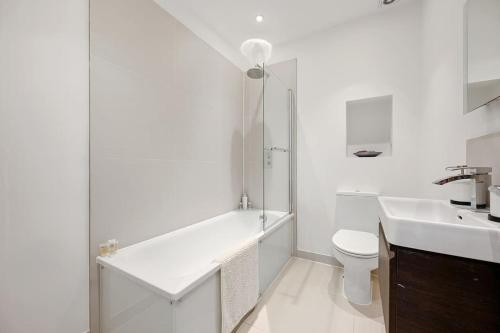 a bathroom with a tub and a toilet and a sink at Ealing Broadway - Lovely 2-bedroom flat with offstreet parking in Ealing