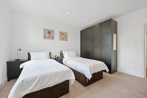 a bedroom with two beds and a large headboard at Ealing Broadway - Lovely 2-bedroom flat with offstreet parking in Ealing