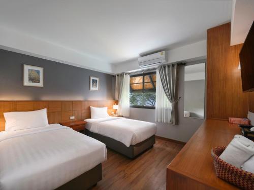 a hotel room with two beds and a window at Estia Chiangmai -SHA Plus in Chiang Mai