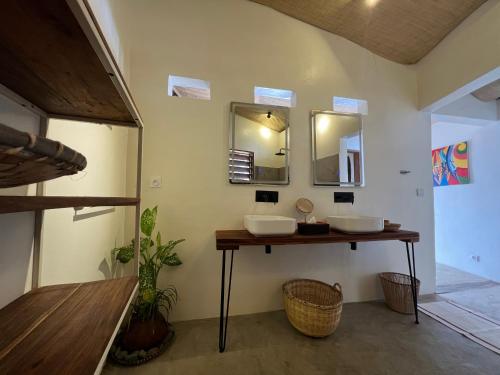 a bathroom with two sinks and two mirrors at Canopee Lodge in Nosy Komba