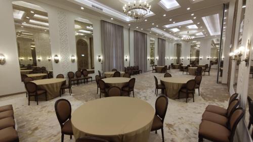 Luxury Sea View Apartment with Amazing Amenities at Pearl Qatar في الدوحة: قاعة احتفالات مع طاولات وكراسي في غرفة