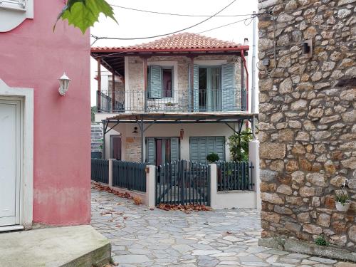 une maison rose avec une clôture devant elle dans l'établissement Neon, à Larissa