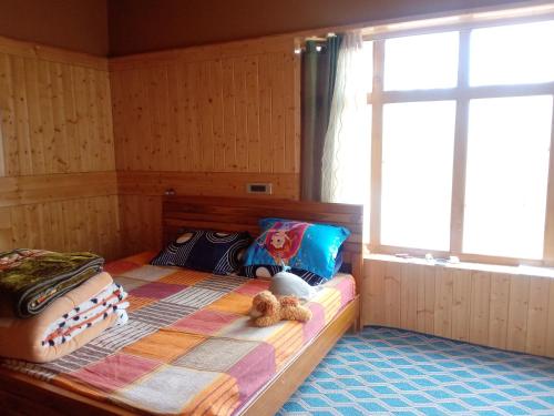 a bedroom with a bed with a teddy bear on it at Tsabgyat Homestay in Leh