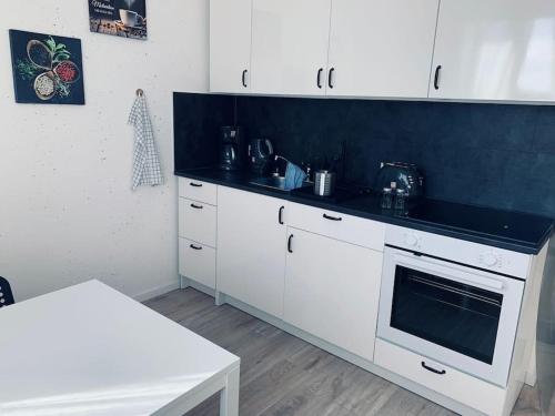 cocina con armarios blancos y encimera negra en cozy Apartment in Cottbus Work 2 en Cottbus