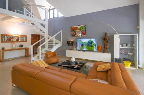 a living room with a brown couch and a staircase at Balinea Villas in Pereybere