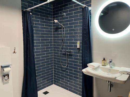 y baño con ducha de azulejos azules y lavamanos. en Beau Rivage Hôtel-Restaurant, en Luc-sur-Mer