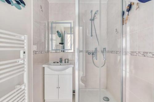 une salle de bain blanche avec une douche et un lavabo dans l'établissement Cabourg Emeraude 2 étoiles plage et thalasso 100m parking gratuit, à Cabourg