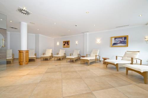 a waiting room with white chairs and paintings on the wall at Ortnerhof - Ihr Zuhause am Fuße der Alpen in Ruhpolding
