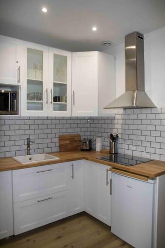 une cuisine avec des armoires blanches et un évier dans l'établissement Another brick in the wall Apartment in Paris Sleeps 9, à Paris