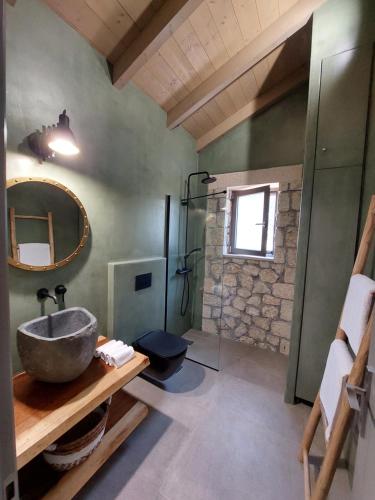 a bathroom with a sink and a mirror and a shower at Elaiopetra Kefalonia - Stonehouse Hideaway with pool - Modern Luxury with Serene Sea and Mountain Views in Metaxáta