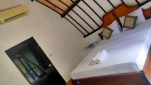 1 dormitorio con 1 cama y TV en una habitación en Meno Lodge, en Gili Meno