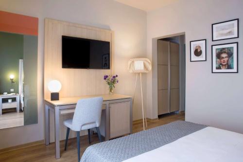 a bedroom with a desk with a tv and a bed at Central Hotel, Trademark Collection by Wyndham in Bucharest