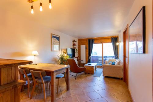 a dining room with a table and chairs and a living room at Bel appartement au calme vue vallée in Sainte-Foy-Tarentaise
