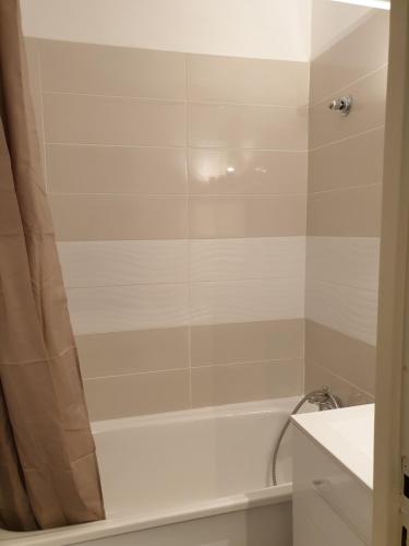 a bathroom with a bath tub with a shower curtain at Résidence les Campanules appartement entièrement rénové à 100m des pistes in Villarodin-Bourget