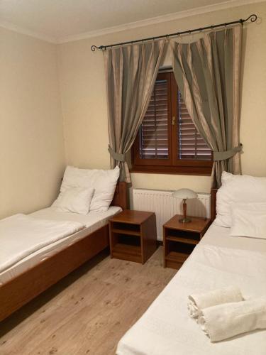 2 camas individuales en una habitación con ventana en Wildente Vadászház, en Tamási