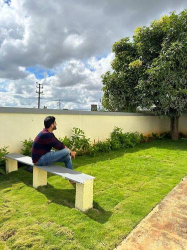a man sitting on a bench in the grass at Krishna Homes in Bengaluru