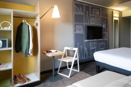 a room with a bed and a desk with a chair at ibis Pontorson Baie Du Mont Saint Michel in Saint-Georges-de-Gréhaigne