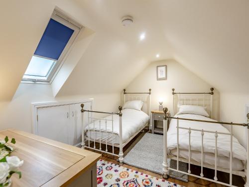 two beds in a attic bedroom with a window at Two Chainbridge Barns in Wainfleet All Saints
