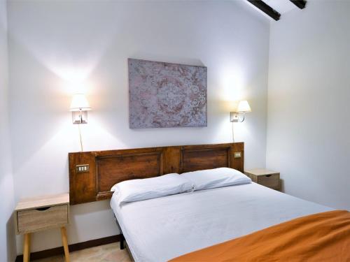 a bedroom with a bed and two tables and a painting at Charming apartment in Mantignana with shared pool in Mantignana
