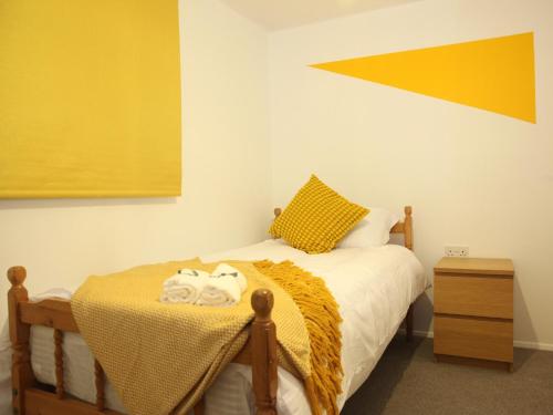 um quarto com uma cama com uma parede amarela em The Annexe em Thorpe