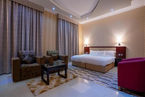 een hotelkamer met een bed en twee stoelen bij Vista City Hotel in Dubai
