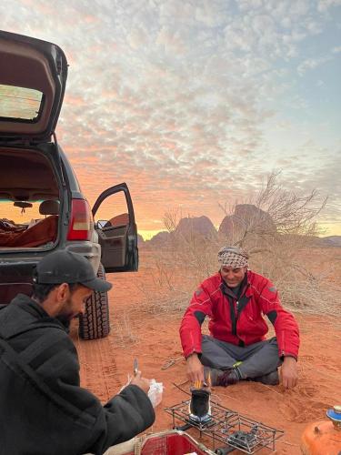 two men sitting on the ground in the desert at golden day in Wadi Rum