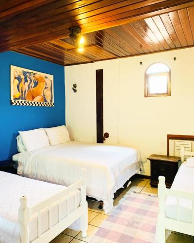 two beds in a room with blue walls and wooden ceilings at Pousada Tropicana in Abraão