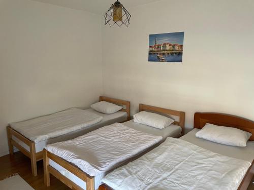 Habitación con 3 camas y una foto en la pared. en Stan Tea siroki brijeg, en Široki Brijeg